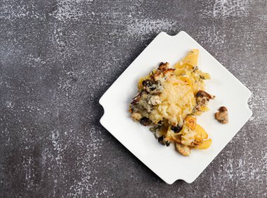 Kare tabakta mantarlı ve peynirli patates güveci. Üst manzara, düz uzanma