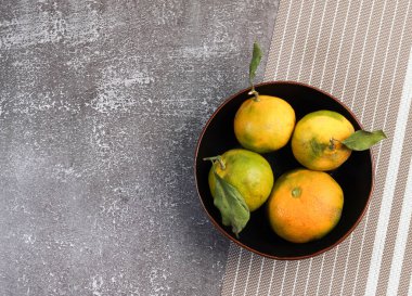 Siyah arka planda yaprakları olan mandalinalar. Üst manzara, düz uzanma