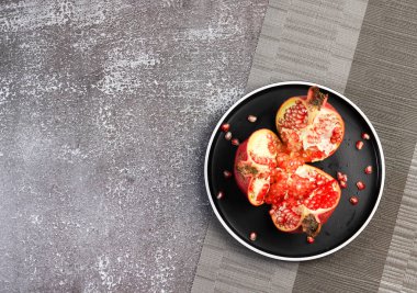 Siyah arka planda yuvarlak bir tabakta nar. Üst manzara, düz uzanma