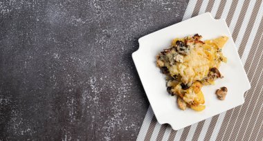 Kare tabakta mantarlı ve peynirli patates güveci. Üst manzara, düz uzanma