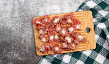 Dikdörtgen bir zeminde çiğ tavuk taşları koyu gri bir zemin üzerinde ahşap tahta kesiyor. Üst manzara, düz uzanma