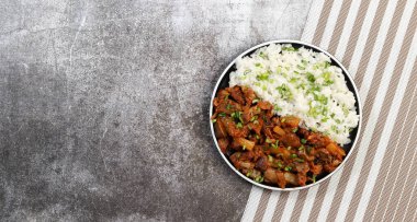 Koyu gri bir arka planda yuvarlak tabakta haşlanmış pirinçli tavuk taşlıkları. Üst manzara, düz uzanma