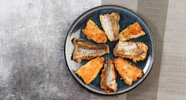 Koyu gri arka planda yuvarlak tabakta balık filetosu. Üst manzara, düz uzanma