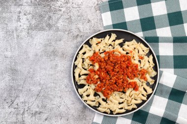 Koyu gri arka planda yuvarlak tabakta geleneksel makarna bolonez. Üst manzara, düz uzanma