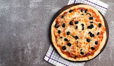 Koyu arkaplanda yuvarlak ahşap kesme tahtasında mozzarella ve zeytinli Rustik pizza. Üst manzara, düz uzanma