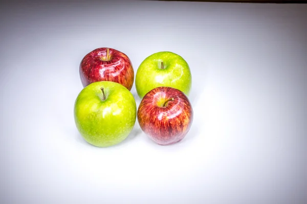 Four red and green apples in square composition painted with light — Stock Photo, Image