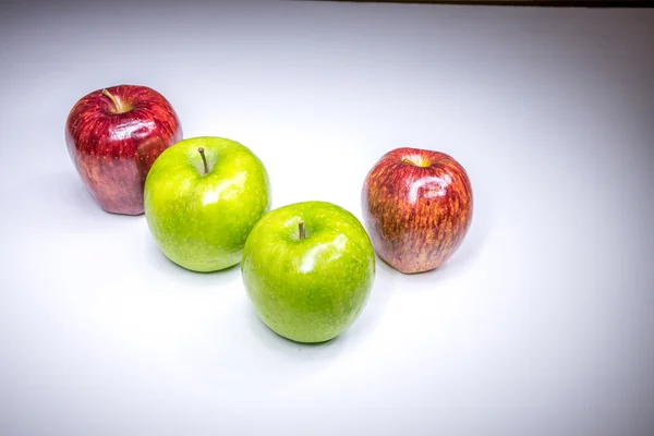 Four red and green apples in four finger composition painted with light — Stock Photo, Image