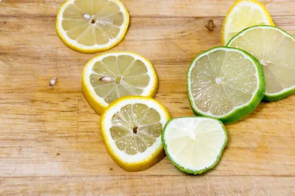 Vápno a plátky citronu na dřevěné desce — Stock fotografie