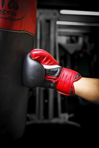 Golpear un saco de boxeo con guantes de boxeo rojos — Foto de Stock