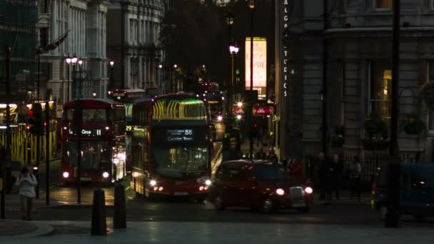 Londýn - 12 listopadu 2014: Červené autobusy na Charing Cross po západu slunce — Stock video