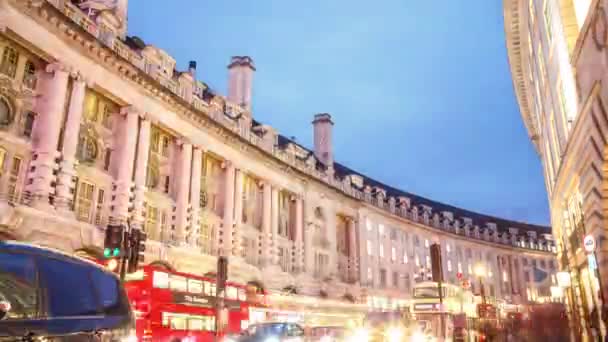 Londen - September 23 2015: Lage hoek tilt omlaag nacht schot vanaf het begin van de straat van de Regent in Londen, naast de Piccadilly Circus. 'S avonds verkeer met rode bussen en zwarte cabines in 2015. — Stockvideo