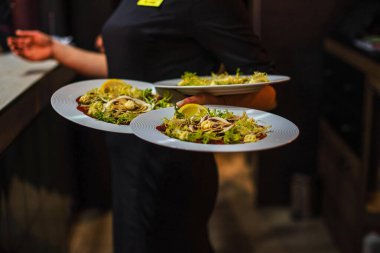 Garson elinde üç tabak tutuyor.