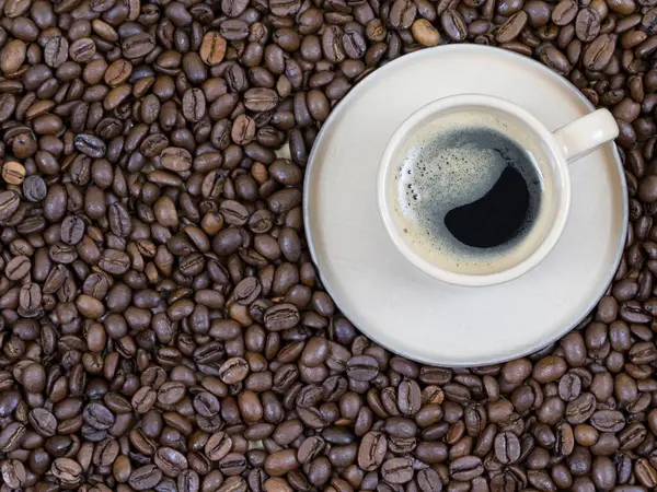En kopp kaffe på bakgrunden av kaffebönor. Utsikt ovanifrån — Stockfoto
