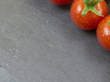 Siyah taş zemin üzerinde kırmızı domatesler. Kapat..