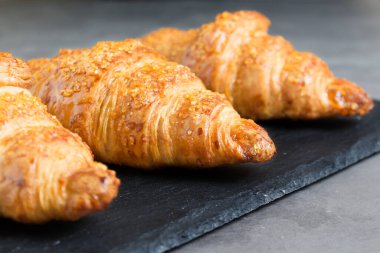 Siyah taşlı arka planda üç lezzetli kruvasan. Fransız yemeği. Kapatın. Alçak tuş