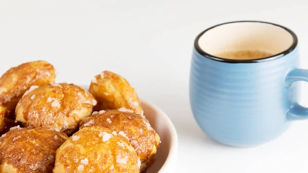 Chouquettes sopros franceses com perles de açúcar na placa com xícara azul de café. Choux pastelaria padarias francesas clássicas. — Fotografia de Stock