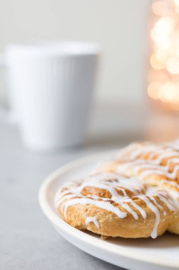 Tarçınlı çörek ya da tarçınlı çörek tabakta beyaz fincan kahve. Klasik Amerikan ya da Fransız fırınları. Bokeh