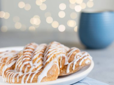 Tarçınlı çörek ya da tarçınlı çörek tabakta mavi fincan kahve. Klasik Amerikan ya da Fransız fırınları. Bokeh