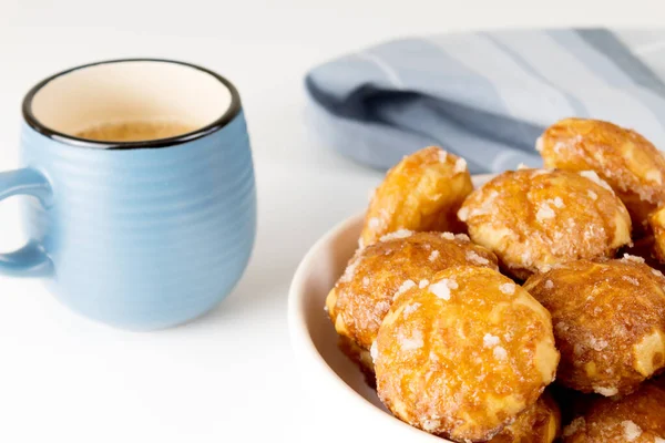 Franse chouquettes puffs met perziken suiker op bord met blauwe kop koffie. Choux gebak Klassieke Franse bakkerijen. — Stockfoto