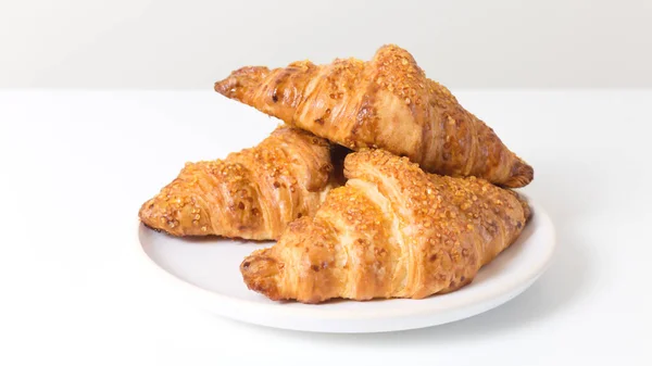 Placa Blanca con tres sabrosos croissants sobre fondo blanco. Comida francesa — Foto de Stock