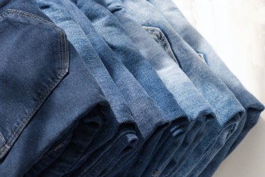 Açık arkaplanlı bir kot pantolon yığını. Kapatın. Güneş ışığı. Çapraz