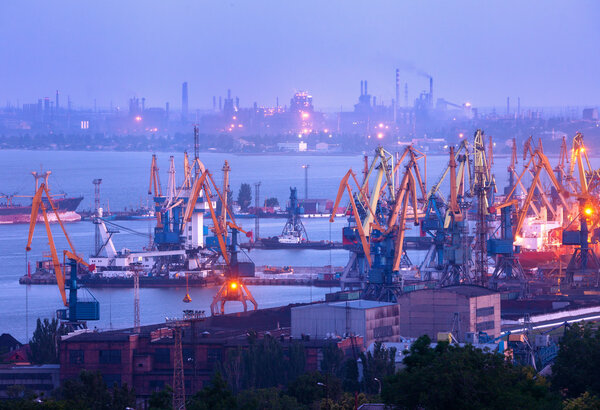 Sea commercial port at night against working steel plant