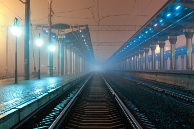 Tren istasyonunda gece. Sisin içinde tren platformu. Demiryolu