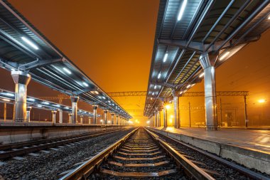 Tren istasyonunda gece. Sisin içinde tren platformu. Demiryolu