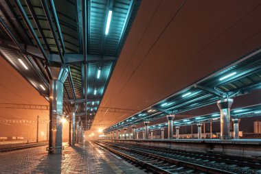 Tren istasyonunda gece. Sisin içinde tren platformu. Demiryolu