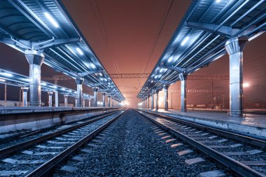 Tren istasyonunda gece. Sisin içinde tren platformu. Demiryolu