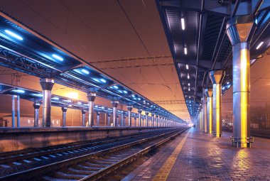 Tren istasyonunda gece. Sisin içinde tren platformu. Demiryolu