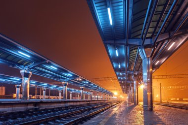 Tren istasyonunda gece. Sisin içinde tren platformu. Demiryolu