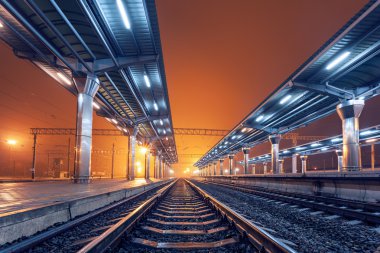 Tren istasyonunda gece. Sisin içinde tren platformu. Demiryolu