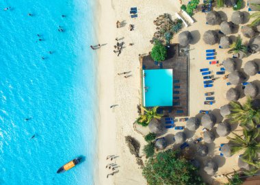 Havuz manzarası, palmiyeli, şemsiyeli, yüzen insanlar, gün batımında tekne, mavi okyanus. Nungwi, Zanzibar adasında yaz tatili. Tropik bir manzara. Açık gök mavisi. Üst görünüm