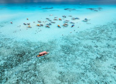 Mnemba Adası 'nın Zanzibar, Tanzanya' daki kumsalının kristal berrak turkuaz suyundaki turistik tekne ve yatların havadan görüntüsü. Tropikal Hint Okyanusu lagünü, mercan resifi, yaz seyahatleri, insansız hava aracı manzarası.