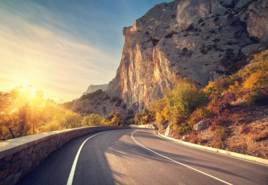 Gündoğumu, sonbahar ormandaki asfalt yol. Kırım Dağları