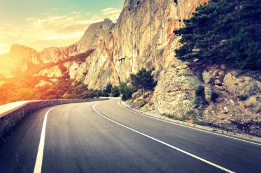 Yaz ormanında gün batımında asfalt yolda. Kırım Dağları