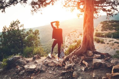 Dağda günbatımında duran genç kadın. Yaz manzara
