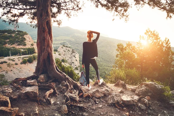 Dağda günbatımında duran genç kadın. Yaz manzara