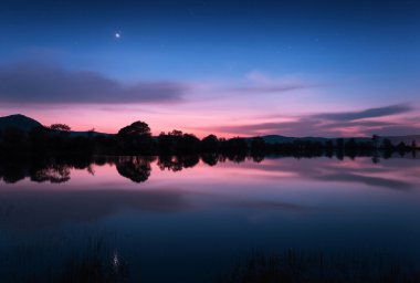 Yıldız ve suda yansıyan bulutlar dağ gölü. Gece