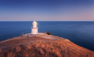 Gün batımında okyanus sahil şeridi üzerinde güzel beyaz fener. Manzara