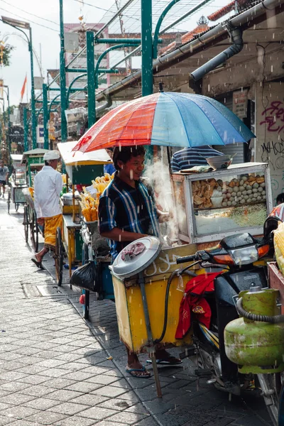 Indonesian food vendor hides from the rain, Ubud, Bali — Stock Photo, Image