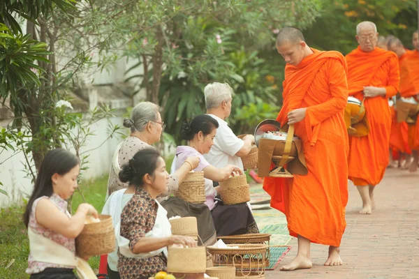 People giving alms to buddhist monks on the street,  Luang Prabang — Stock Photo, Image