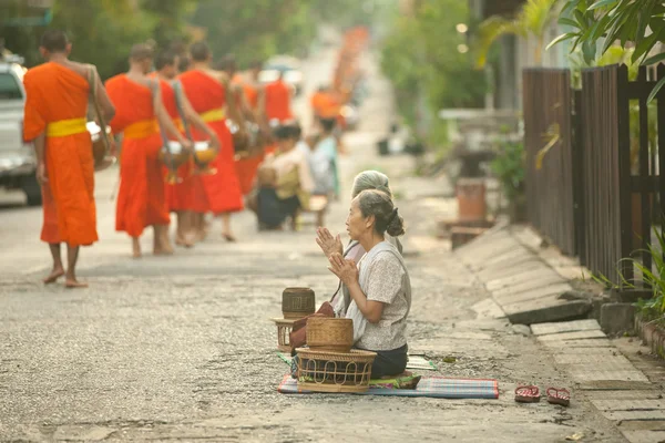 People giving alms to buddhist monks on the street,  Luang Prabang — Stock Photo, Image