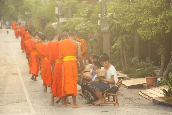 People giving alms to buddhist monks on the street,  Luang Prabang — Stock Photo, Image