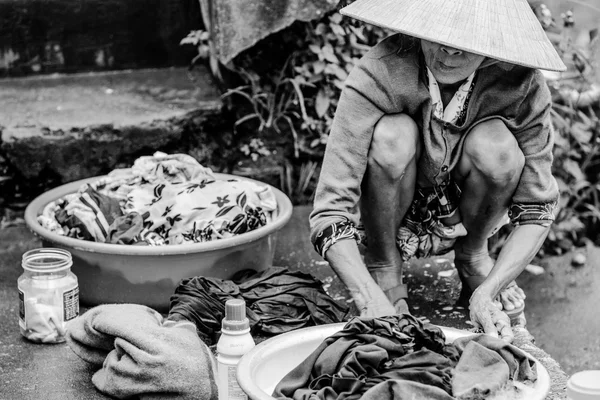 Velha mulher vietnamita está lavando roupas na margem do rio — Fotografia de Stock