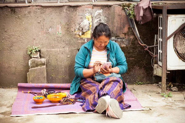 Tibetansk kvinna med en smartphone på gatan marknaden — Stockfoto