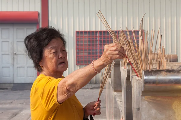 Gammal kvinna bränner rökelse i Kuan Yin tempel — Stockfoto