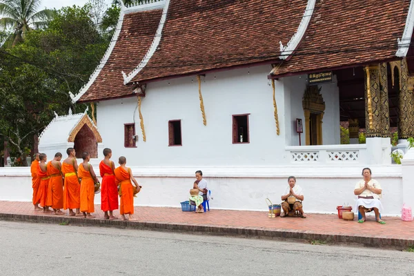 Буддийские монахи собирают подаяние у людей на улице Луангпрабанг, Лаос — стоковое фото