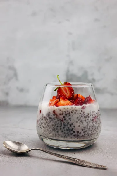 Dessert made of lactose-free milk with chia seeds and strawberries in a glass on a gray background. Clean food, detox, weight loss concept. A recipe for a low-carb diet.